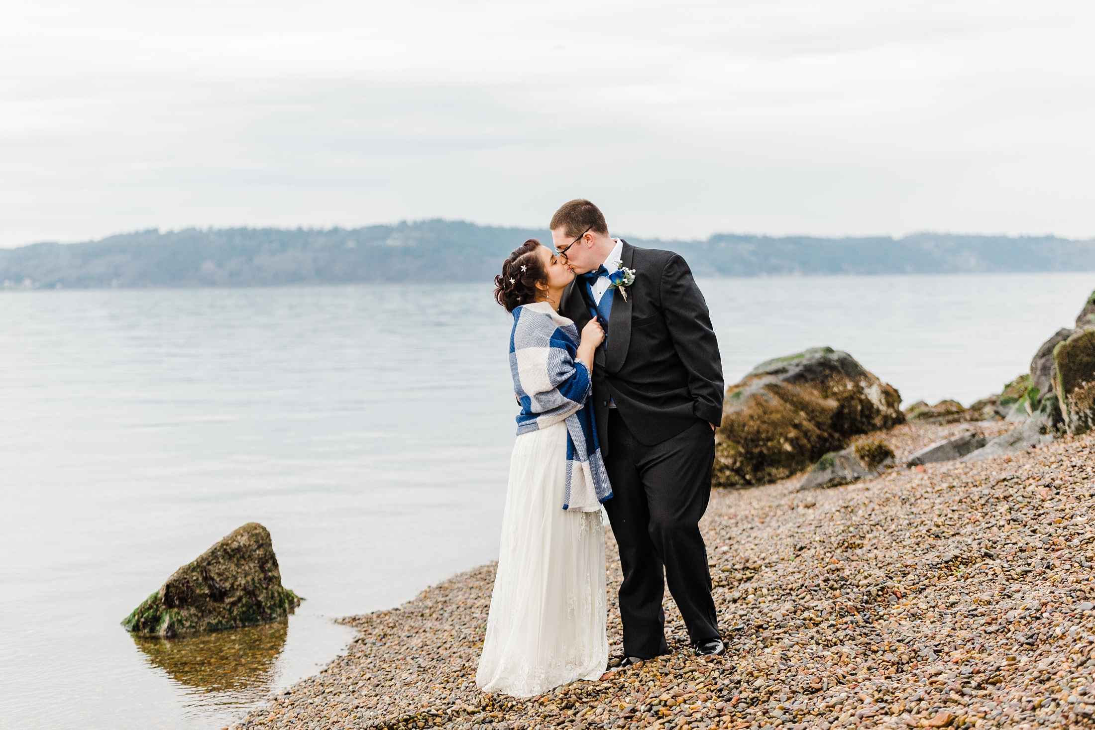 bride and groom kiss on the rocky beach