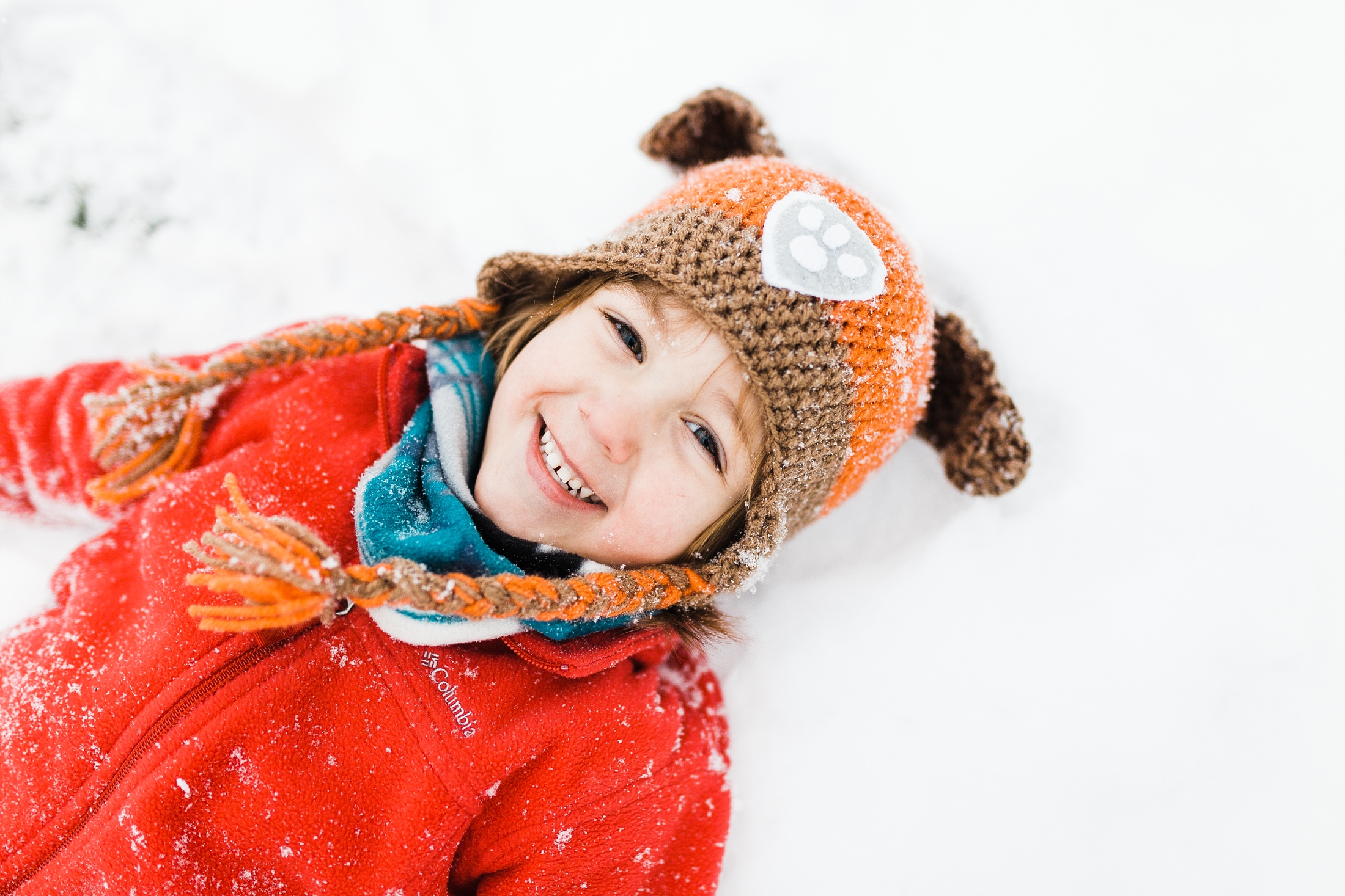 up close photo of four year old laying in snow so happy