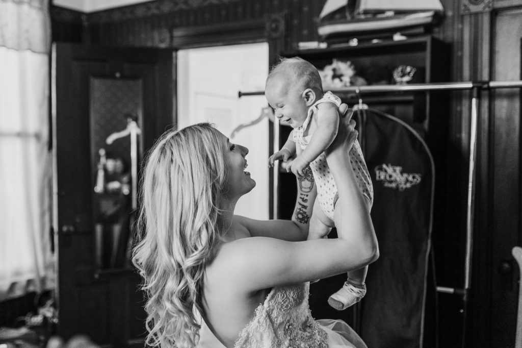 woman holds baby above face to face smiling