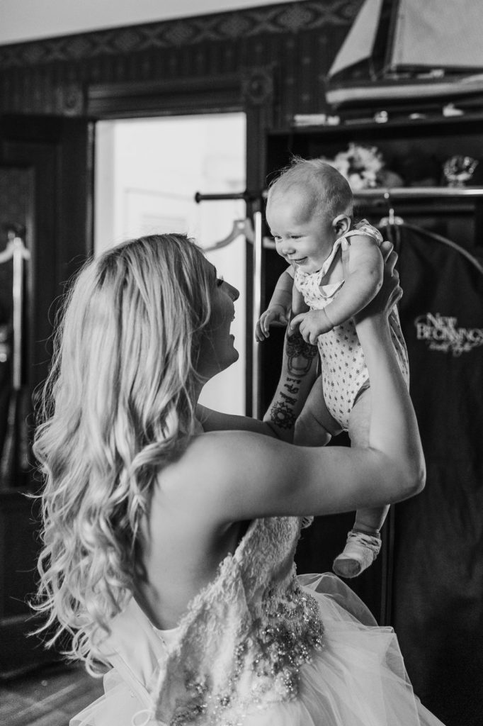 Bride getting ready holds baby up in the air